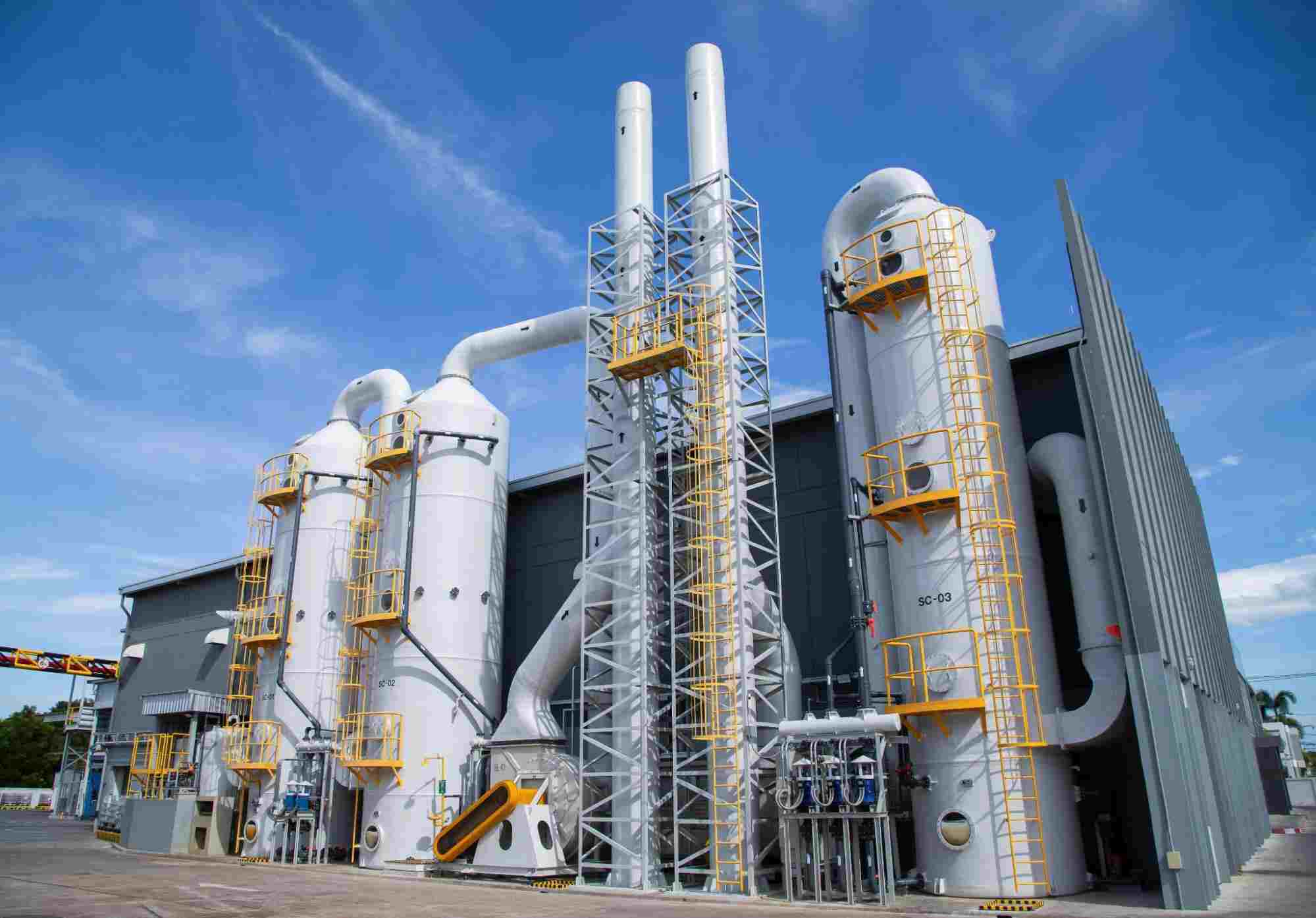 Industrial hydrogen sulfide treatment system with large vertical scrubber towers and processing equipment at a gas treatment facility under a blue sky.