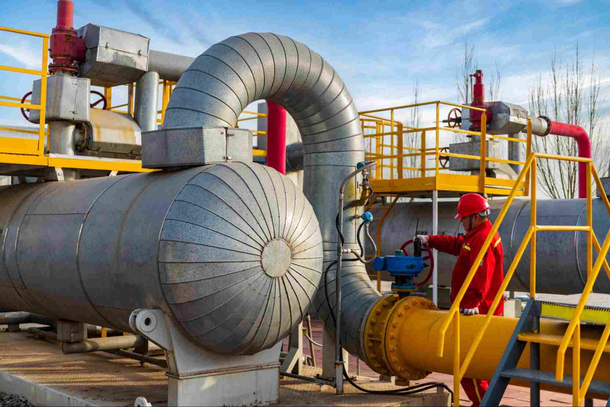 Industrial gas processing equipment with an operator monitoring pipelines and treatment systems used for H₂S removal from gas in a natural gas processing facility.